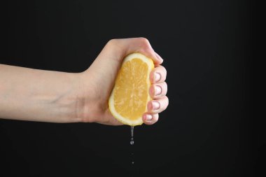 Siyah arka planda limon sıkan kadın, yakın plan.