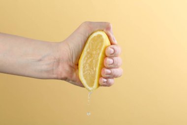 Sarı arka planda limon sıkan kadın, yakın plan.