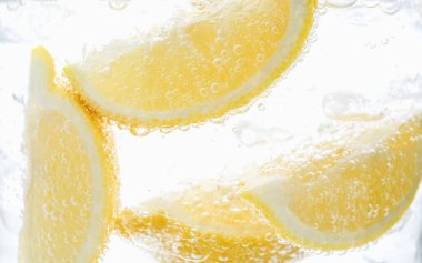 Beyaz arka planda limon dilimleri ile soda tazeleniyor, yakın plan.