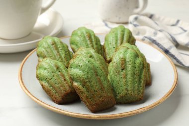 Lezzetli Matcha Madeleine kekleri beyaz masada, yakın plan.