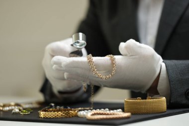 Masadaki lüks mücevherleri değerlendiren eksper, yakın plan.