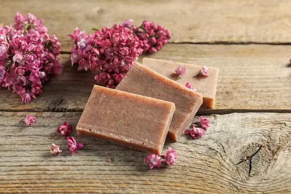 Sabun çubukları ve ahşap masada leylak çiçekleri, yakın plan.