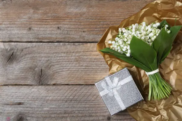 Bir buket güzel vadi zambağı ve ahşap arka planda hediyeler, üst manzara. Metin için boşluk