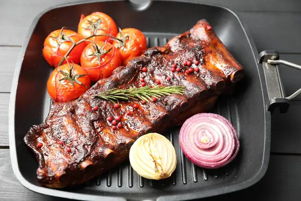 Biberiyeli domuz pirzolası, domates ve soğan. Gri ahşap masada, yakın plan.