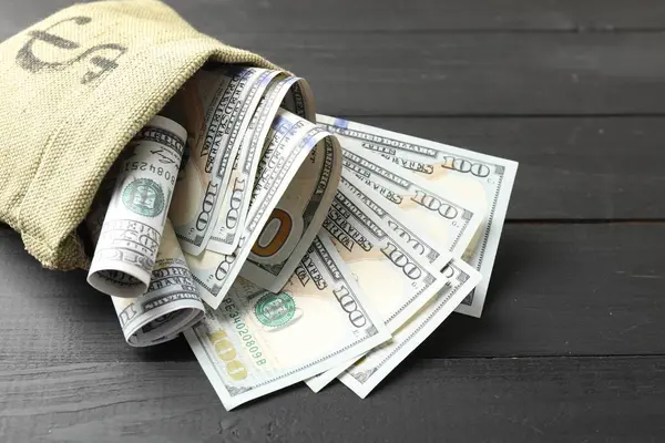 Üzerinde dolar banknotları olan para çantası. Gri ahşap masa, yakın plan.