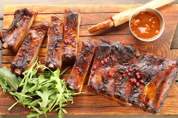 Lezzetli pirzola, sos, roka ve ahşap masa fırçası.