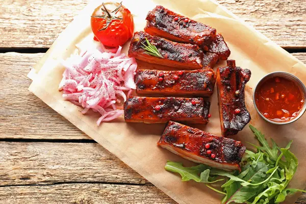 Lezzetli domuz pirzolası, sos, roka ve soğan ahşap masa, üst manzara.