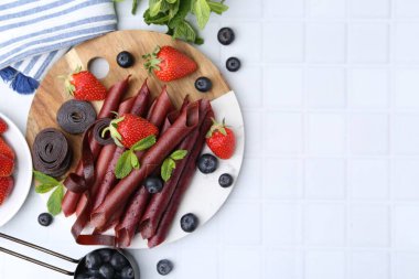 Lezzetli meyve dürümleri, çilekler, yaban mersinleri ve nane şekeri beyaz fayanslı masa, düz yatak. Metin için boşluk