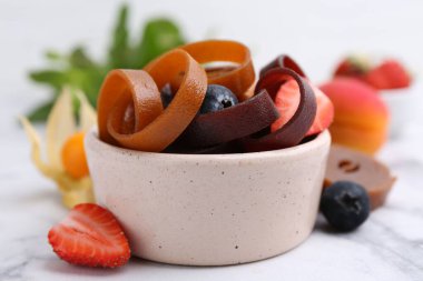 Lezzetli meyve derisi kase içinde yuvarlanır ve beyaz mermer masada böğürtlenler, yakın plan.