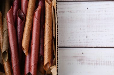 Lezzetli meyve derisi, beyaz ahşap masada, karton kutuda yuvarlanıyor. Metin için boşluk