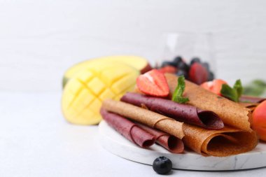 Lezzetli meyve dürümleri, nane, mango ve böğürtlenler ışık masasında, yakın plan. Metin için boşluk