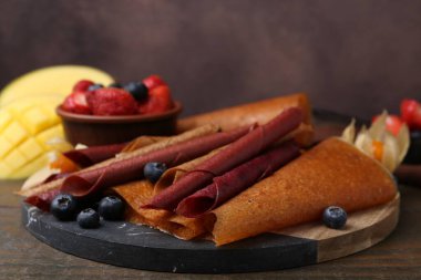 Lezzetli meyve dürümleri ve böğürtlenler ahşap masada, yakın plan.