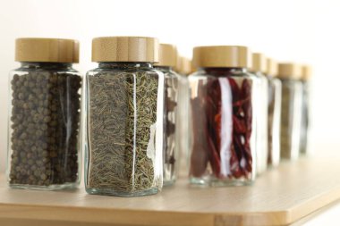 Kapalı alanda, ahşap masadaki kavanozlardaki farklı aromatik baharatlar.