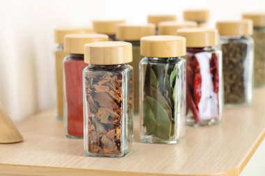 Kapalı alanda, ahşap masadaki kavanozlardaki farklı aromatik baharatlar.