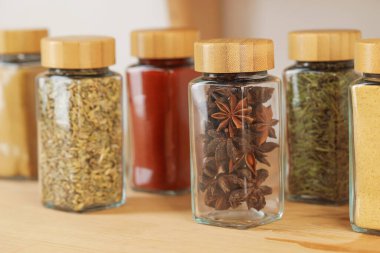 Kapalı alanda, ahşap masadaki kavanozlardaki farklı aromatik baharatlar.
