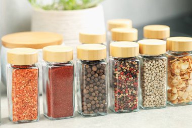 Açık gri masa üzerinde kavanozlarda çok farklı aromatik baharatlar var.