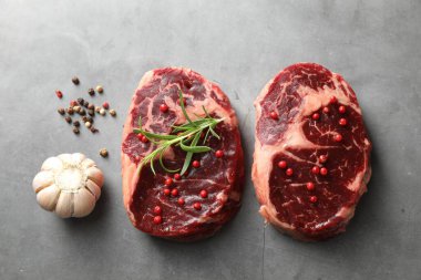 Çiğ et parçaları ve baharatlar gri dokulu masa üzerinde, düz yatıyordu.