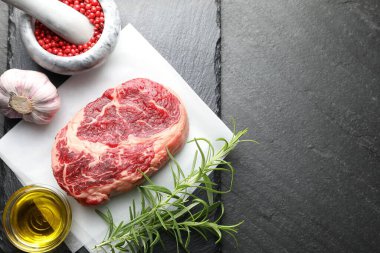 Bir parça çiğ et ve baharat siyah masada, düz yerde. Metin için boşluk