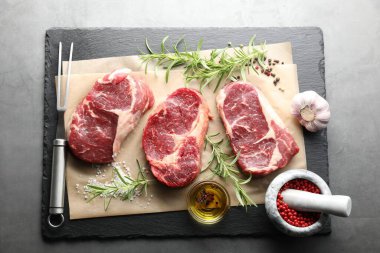 Çiğ et, baharat ve çatal parçaları gri masada, düz yatıyordu.