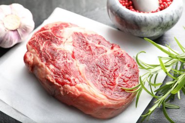 Bir parça çiğ et ve baharat siyah masada, yakın plan.