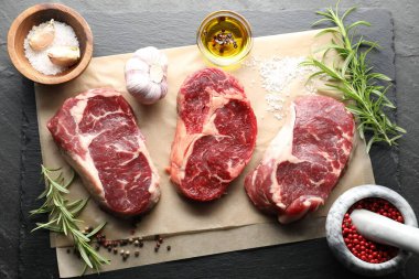 Çiğ et parçaları ve baharatlar siyah masanın üzerinde, düz yatıyordu.