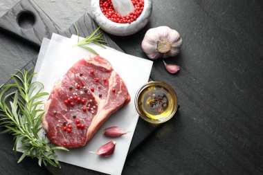 Bir parça çiğ et ve baharat siyah masada, düz yerde. Metin için boşluk