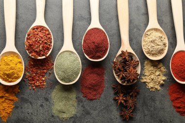 Gri masadaki kaşıklardaki farklı baharatlar düzdü.