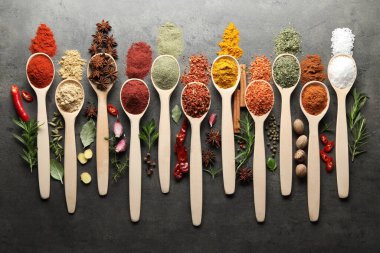 Gri masadaki kaşıklardaki farklı baharatlar düzdü.