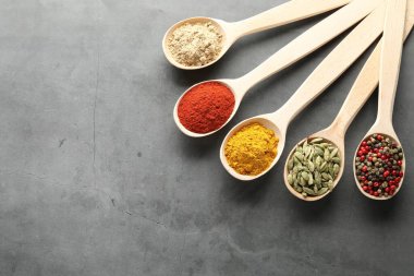 Gri masadaki kaşıklarda bir sürü farklı baharat var. Metin için boşluk