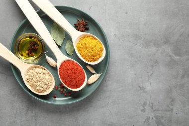 Gri masadaki kaşıklarda birçok farklı baharat, üst manzara. Metin için boşluk