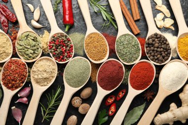 Gri masadaki kaşıklardaki farklı baharatlar düzdü.