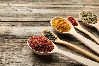 Tahta masadaki kaşıklardaki farklı aromatik baharatlar, yakın plan. Metin için boşluk
