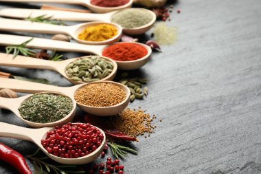 Siyah masada kaşıklardaki farklı aromatik baharatlar, yakın plan. Metin için boşluk