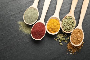 Siyah masadaki kaşıklardaki farklı aromatik baharatlar.