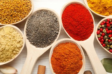 Beyaz ahşap masadaki kaşıklardaki farklı aromatik baharatlar.