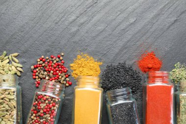 Siyah masadaki kavanozlarda farklı aromatik baharatlar var. Metin için boşluk