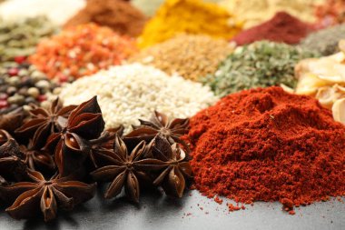 Gri masada farklı aromatik baharatlar, yakın plan.