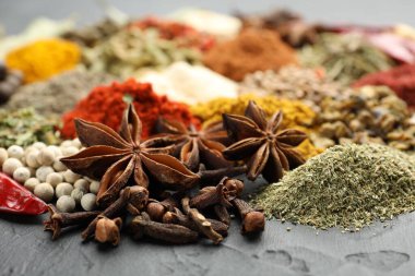 Gri masada farklı aromatik baharatlar, yakın plan.