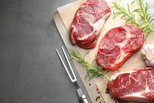 Çiğ et, baharat ve çatal parçaları gri masada, düz yerde. Metin için boşluk