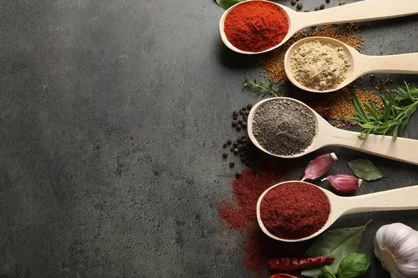 Gri masadaki kaşıklarda bir sürü farklı baharat var. Metin için boşluk