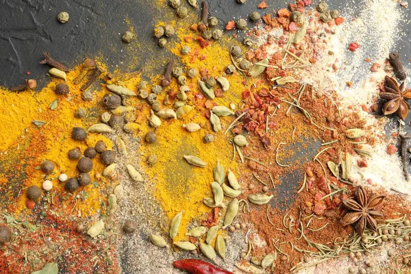 Gri masada farklı aromatik baharatlar, üst görünüm.