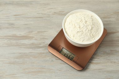 Modern elektronik mutfak terazisi ile ahşap masa üzerinde un kasesi, metin için yer