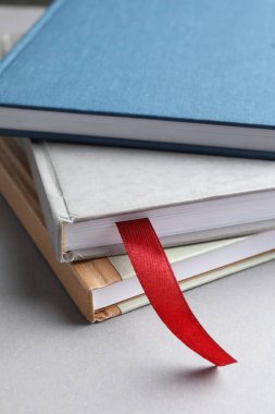 Açık gri masadaki renkli olanlar arasında kırmızı kurdele yer imi olan kitap, yakın plan