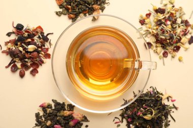 Cam fincanda nefis bitki çayı ve bej arka planda kuru yapraklar.