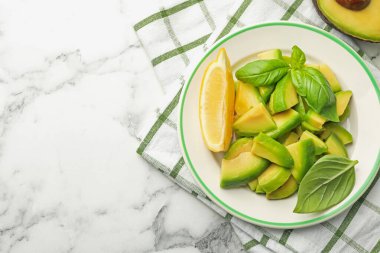 Lezzetli yeşil avokado, fesleğen ve limon beyaz mermer masa, üst manzara. Metin için boşluk