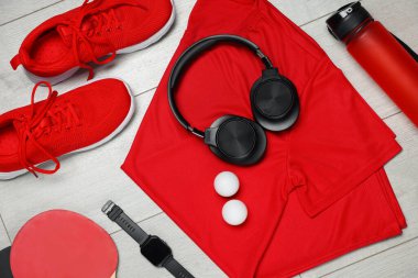 Spor kıyafetleri ve yerde kulaklıkları olan düz bir kompozisyon.