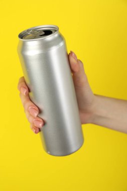 Sarı arka planda teneke kutusu olan kadın, yakın plan.