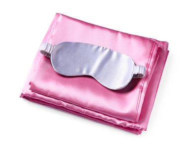 Beyaz arka planda ipek çarşaflar ve uyku maskesi.