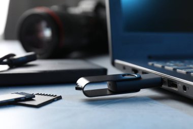 Gri desenli tablo üzerindeki dizüstü bilgisayara ve SD hafıza kartlarına bağlı flaş bellek, yakın plan