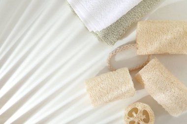 Beyaz masa üzerinde farklı banyo süngeri ve havlular var. Metin için boşluk